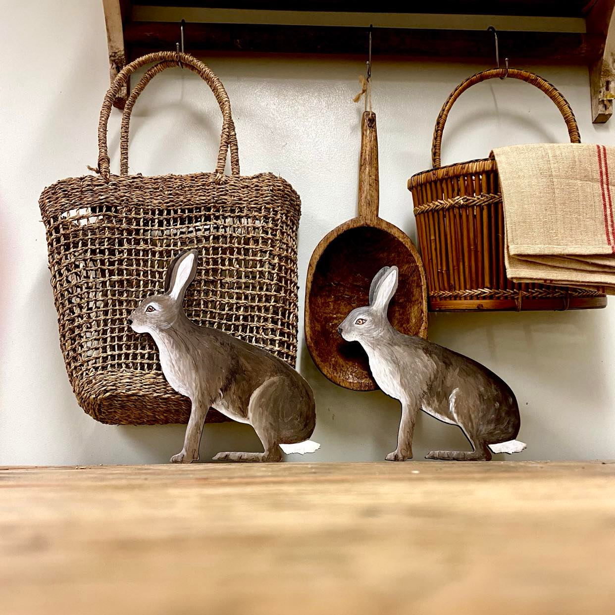 Two handpainted wooden hare ornaments against a vintage handmade kitchenware