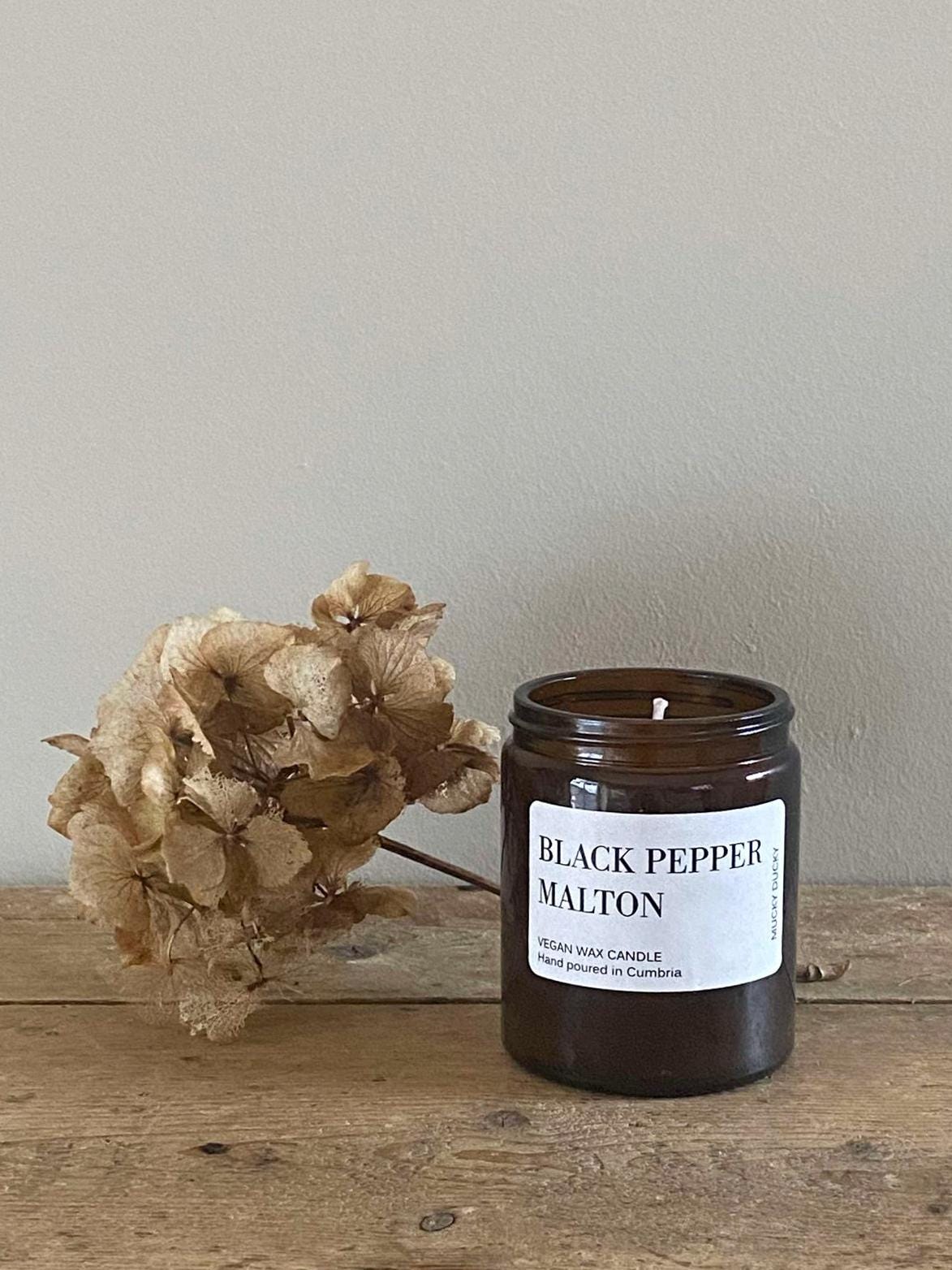 Black pepper scented container candle with a cottagecore background